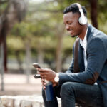 Shot of a young businessman using a smartphone and headphones in the city